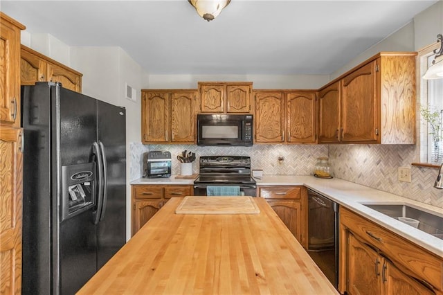 kitchen featuring black appliances, butcher block counters, brown cabinets, and backsplash