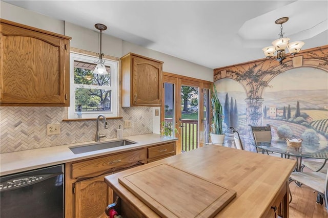 kitchen featuring black dishwasher, a sink, a chandelier, hanging light fixtures, and decorative backsplash