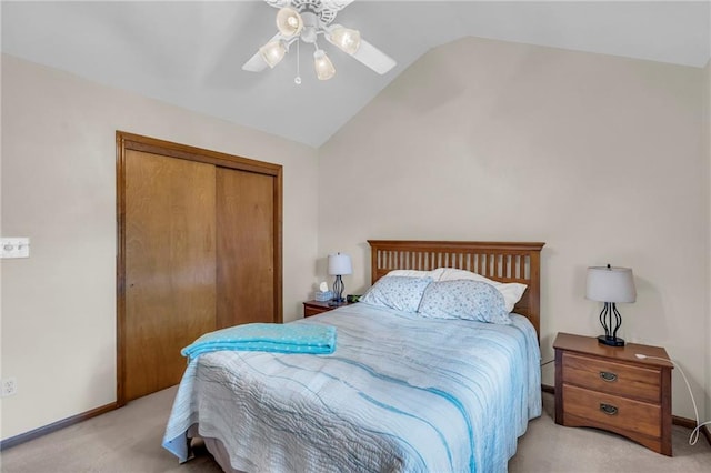 carpeted bedroom with vaulted ceiling, a closet, a ceiling fan, and baseboards
