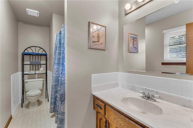 full bathroom with toilet, vanity, and baseboards