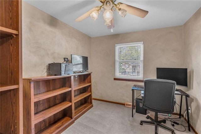 carpeted office space with a ceiling fan and baseboards