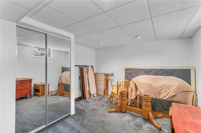 carpeted bedroom with a paneled ceiling and a closet