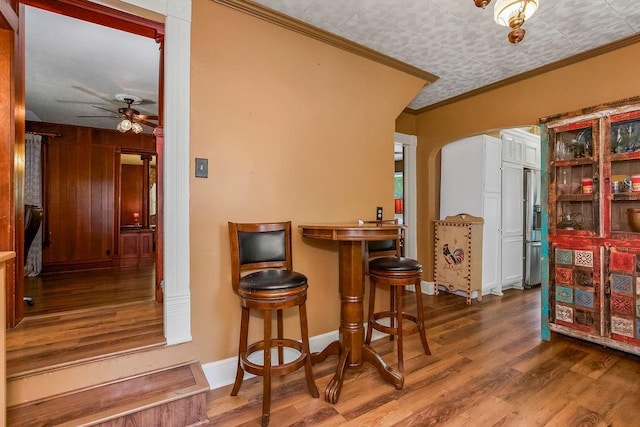 2312 Maple Ave, Leavenworth, KS 66048 - bar with arched walkways, ceiling fan, wood finished floors, stainless steel refrigerator with ice dispenser, and crown molding