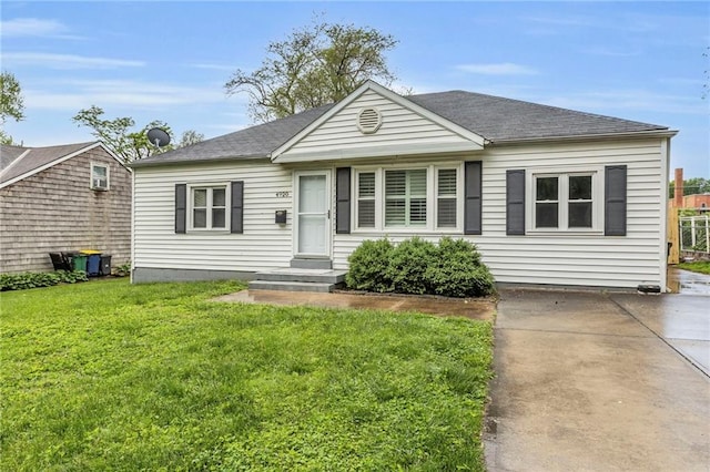 bungalow-style home with a front lawn and roof with shingles
