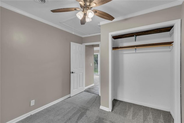 unfurnished bedroom with carpet flooring, crown molding, attic access, baseboards, and a closet
