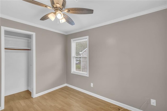 unfurnished bedroom featuring baseboards, ornamental molding, light wood finished floors, and a closet