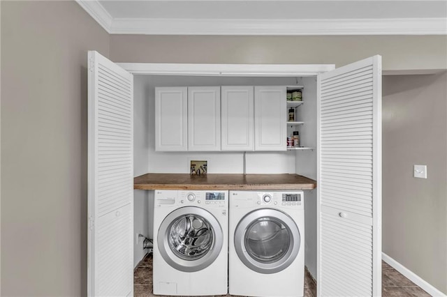 clothes washing area featuring baseboards, ornamental molding, washing machine and dryer, and cabinet space
