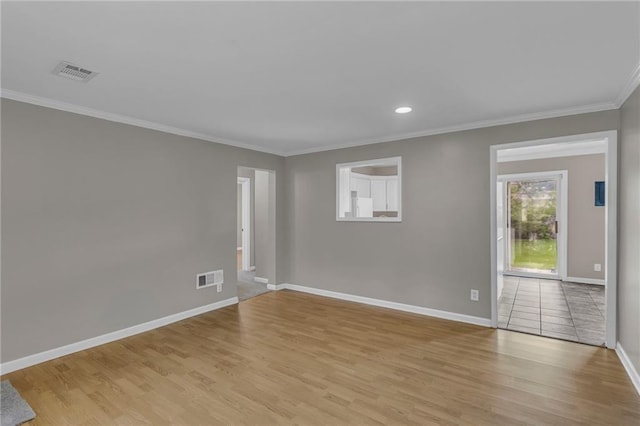 empty room with light wood-style floors, baseboards, ornamental molding, and visible vents