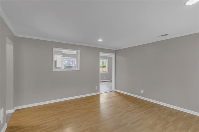 unfurnished room with baseboards, ornamental molding, visible vents, and light wood-type flooring