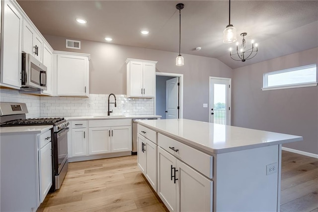 kitchen with a sink, a center island, stainless steel appliances, light wood-type flooring, and visible vents