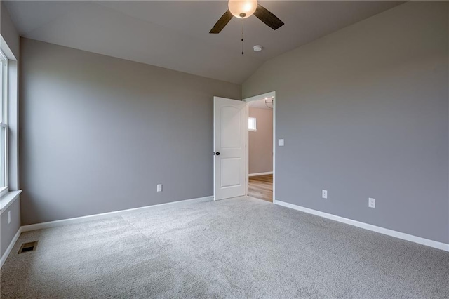 empty room featuring visible vents, a ceiling fan, carpet flooring, and vaulted ceiling