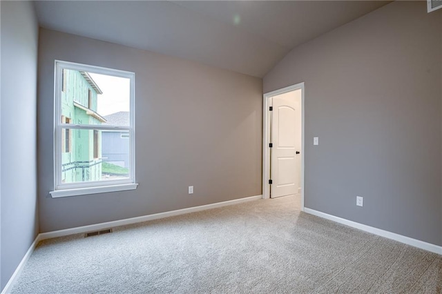 empty room featuring carpet flooring, baseboards, and vaulted ceiling