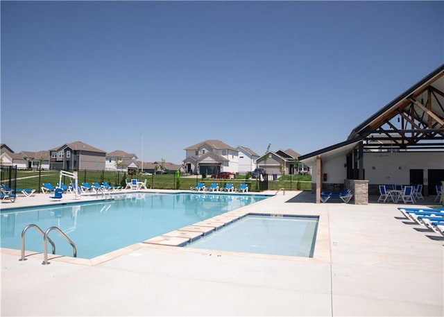 community pool with a residential view, fence, and a patio