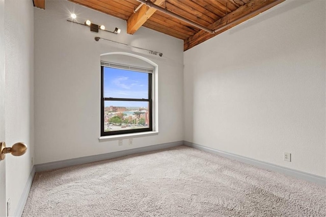 carpeted spare room featuring wooden ceiling, baseboards, and beamed ceiling