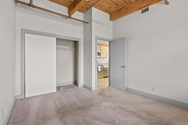 unfurnished bedroom with carpet flooring, beam ceiling, wooden ceiling, visible vents, and a closet