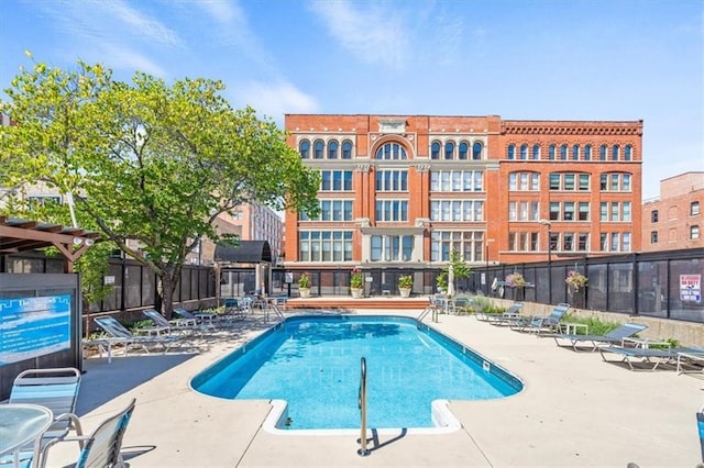 community pool with a patio and fence