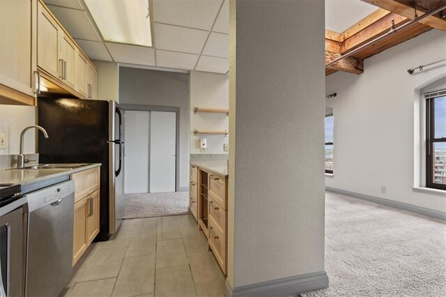 609 Central St Unit 1501, Kansas City, MO 64105 - kitchen with stainless steel appliances, light colored carpet, light brown cabinetry, a sink, and a paneled ceiling