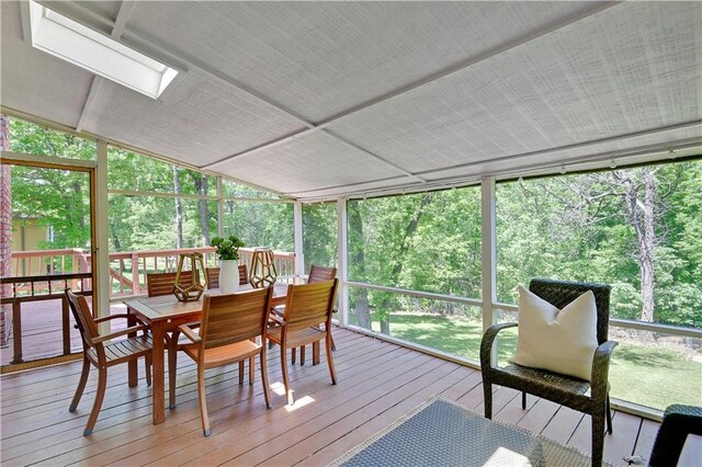 sunroom / solarium featuring outdoor dining area, a skylight, vaulted ceiling, and plenty of natural light