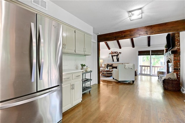 kitchen with freestanding refrigerator, open floor plan, light wood-style floors, light countertops, and a fireplace