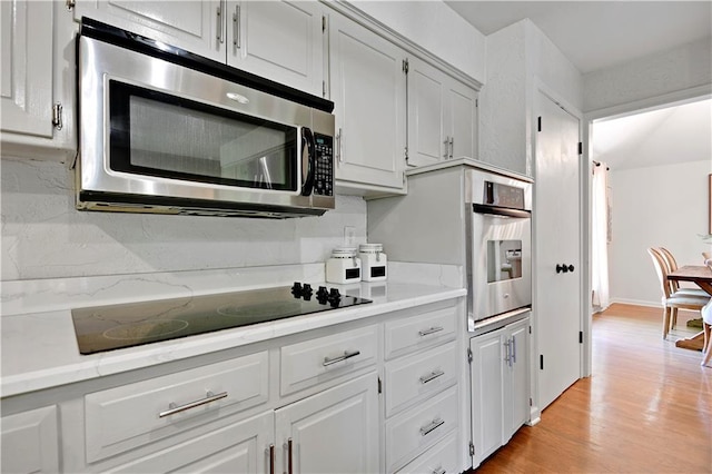kitchen with stainless steel appliances, light countertops, light wood-style floors, and white cabinetry