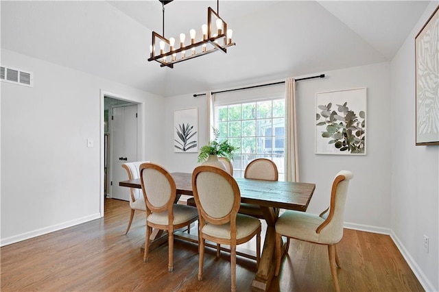 dining area with lofted ceiling, a chandelier, baseboards, and wood finished floors
