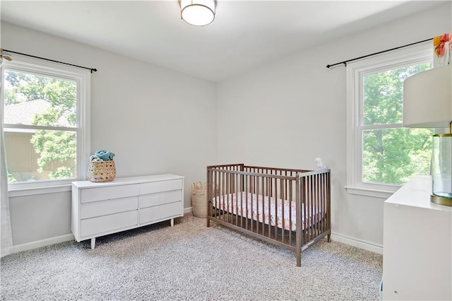 bedroom featuring light carpet, baseboards, and a crib