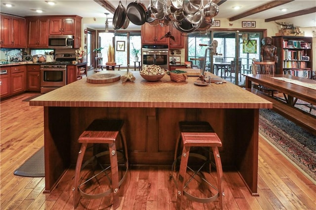 12 Woodland Trl, Warrensburg, MO 64093 - kitchen featuring appliances with stainless steel finishes, light wood-style flooring, a chandelier, a breakfast bar area, and beam ceiling