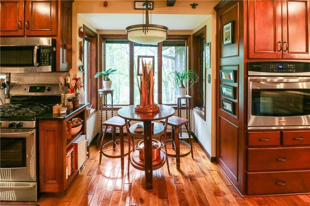 12 Woodland Trl, Warrensburg, MO 64093 - kitchen featuring appliances with stainless steel finishes, hardwood / wood-style flooring, tasteful backsplash, and dark countertops