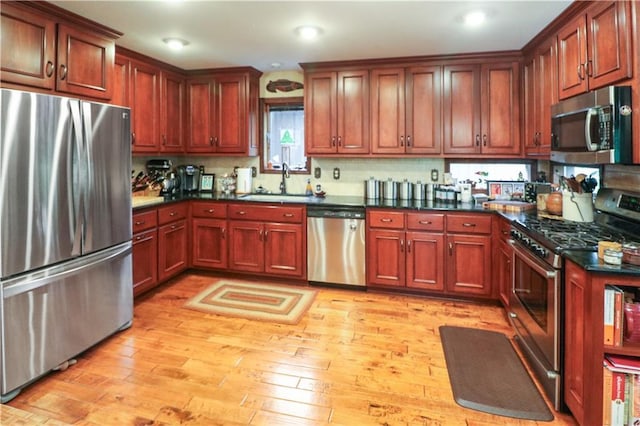 12 Woodland Trl, Warrensburg, MO 64093 - kitchen featuring appliances with stainless steel finishes, a sink, dark countertops, light wood finished floors, and recessed lighting