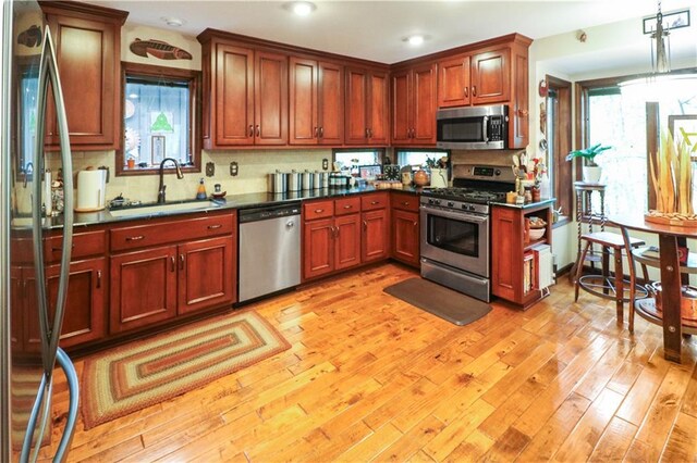 12 Woodland Trl, Warrensburg, MO 64093 - kitchen with appliances with stainless steel finishes, a sink, dark countertops, tasteful backsplash, and light wood-style floors