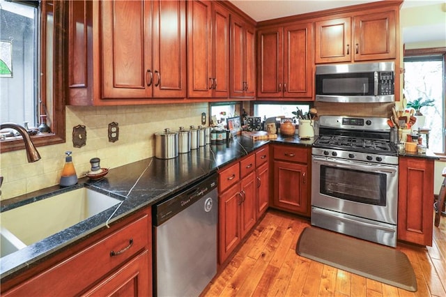 12 Woodland Trl, Warrensburg, MO 64093 - kitchen with stainless steel appliances, a sink, light wood-style floors, tasteful backsplash, and dark stone counters