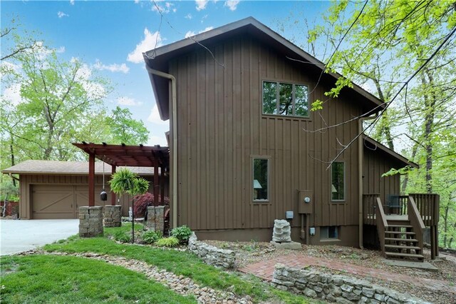 12 Woodland Trl, Warrensburg, MO 64093 - view of home's exterior featuring a garage, driveway, a pergola, and board and batten siding