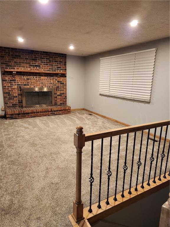 15921 Cantrell Rd, Bonner Springs, KS 66012 - carpeted living area featuring a fireplace, a textured ceiling, and recessed lighting