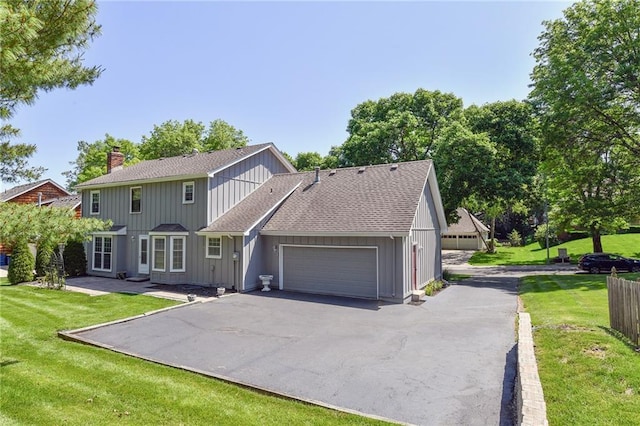 12012 Ensley Ln, Leawood, KS 66209 - view of front of home with an attached garage, asphalt driveway, a front lawn, a shingled roof, and a chimney