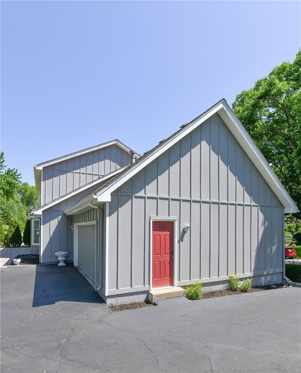 12012 Ensley Ln, Leawood, KS 66209 - view of front facade featuring board and batten siding, an attached garage, and driveway
