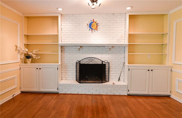 12012 Ensley Ln, Leawood, KS 66209 - unfurnished living room with wood finished floors, a fireplace, recessed lighting, and built in shelves