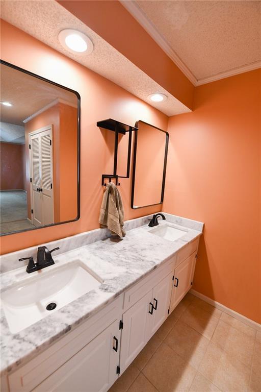12012 Ensley Ln, Leawood, KS 66209 - full bath featuring ornamental molding, double vanity, baseboards, a textured ceiling, and tile patterned flooring