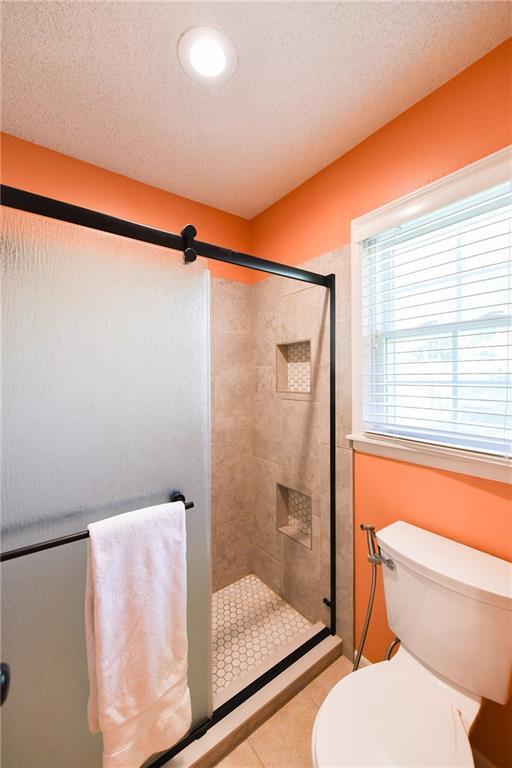 12012 Ensley Ln, Leawood, KS 66209 - full bathroom with a stall shower, toilet, and tile patterned flooring
