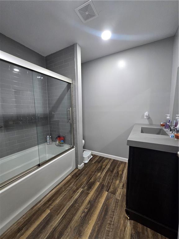 1824 S Grand Ave, Sedalia, MO 65301 - bathroom with vanity, toilet, wood finished floors, visible vents, and bath / shower combo with glass door