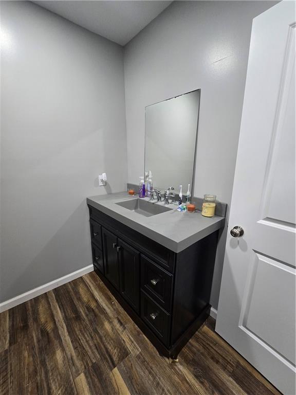 1824 S Grand Ave, Sedalia, MO 65301 - bathroom featuring baseboards, wood finished floors, and vanity