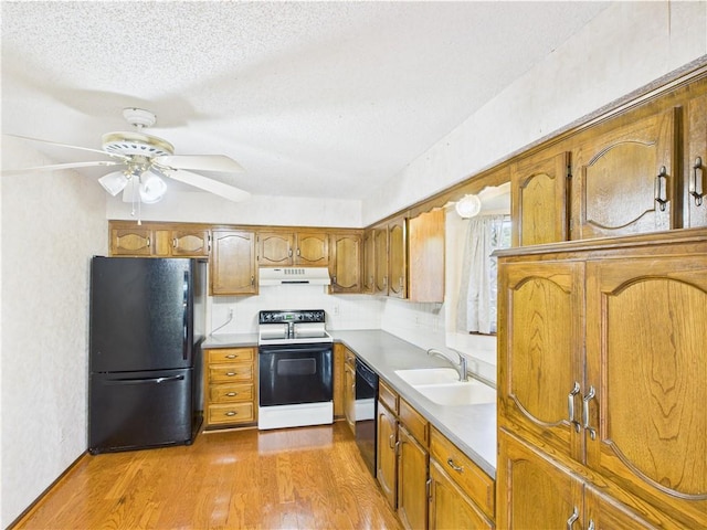 kitchen with black appliances, a sink, range hood, brown cabinetry, and a textured ceiling