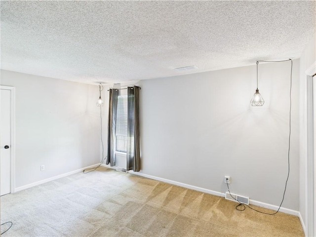 spare room featuring carpet floors, a textured ceiling, and baseboards