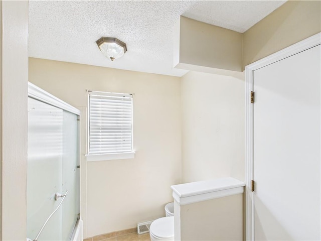 bathroom featuring toilet, tile patterned floors, bath / shower combo with glass door, and baseboards