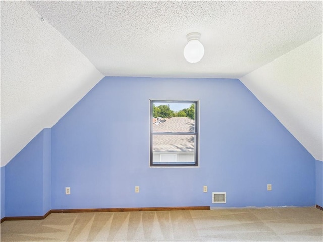 additional living space with lofted ceiling, carpet floors, baseboards, and a textured ceiling