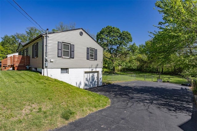 view of side of property featuring a yard, fence, a garage, and driveway