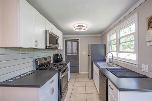 kitchen with a sink, white cabinetry, dark countertops, and appliances with stainless steel finishes