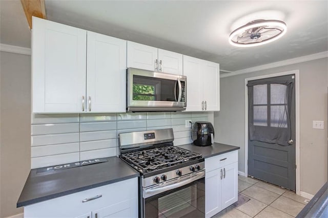kitchen with baseboards, ornamental molding, dark countertops, stainless steel appliances, and tasteful backsplash
