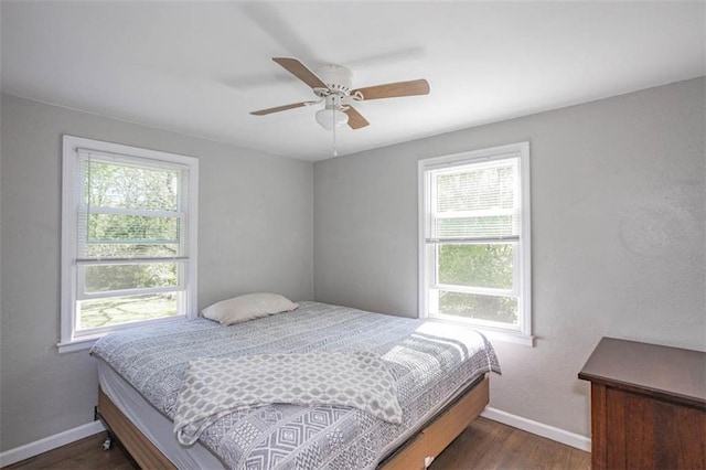 bedroom featuring baseboards, multiple windows, a ceiling fan, and wood finished floors