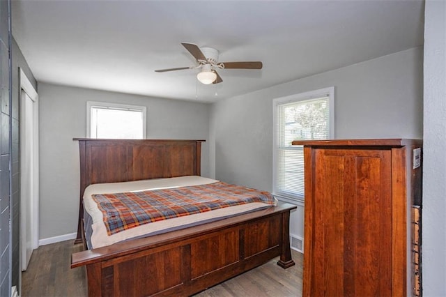 bedroom featuring multiple windows, wood finished floors, and a ceiling fan