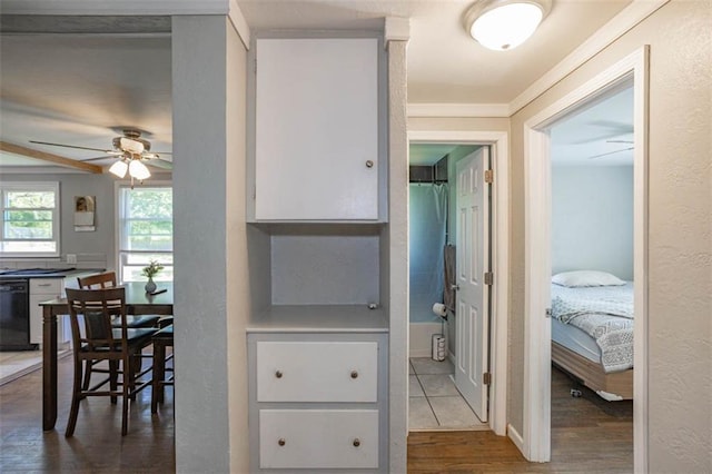 hallway with ornamental molding, a textured wall, and wood finished floors